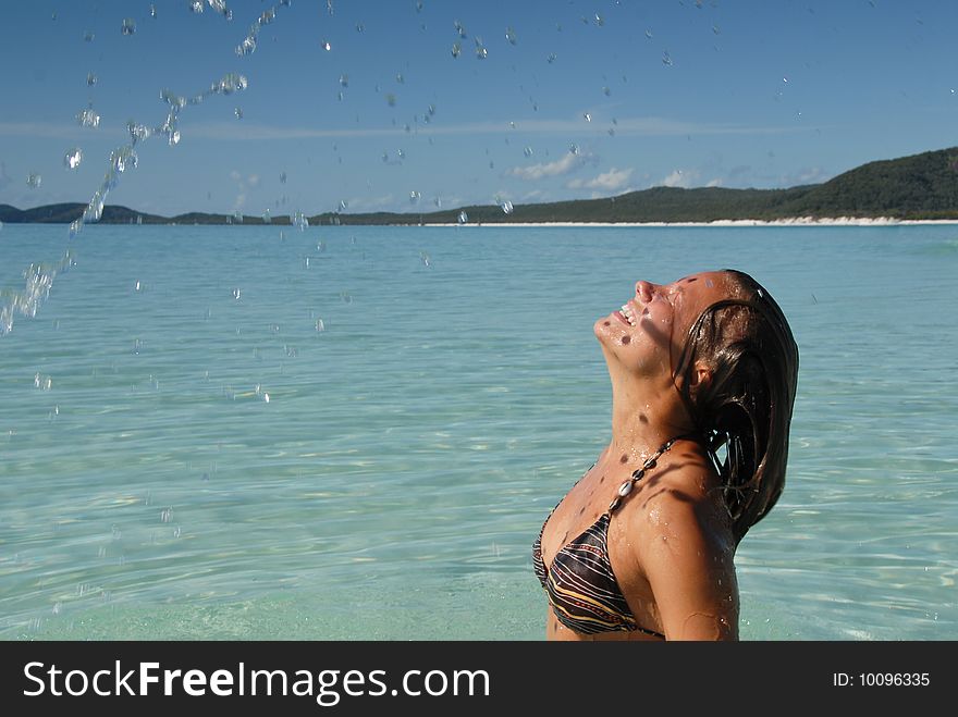 Beautiful young teenage girl flicking hair in turquoise blue water at paradise beach