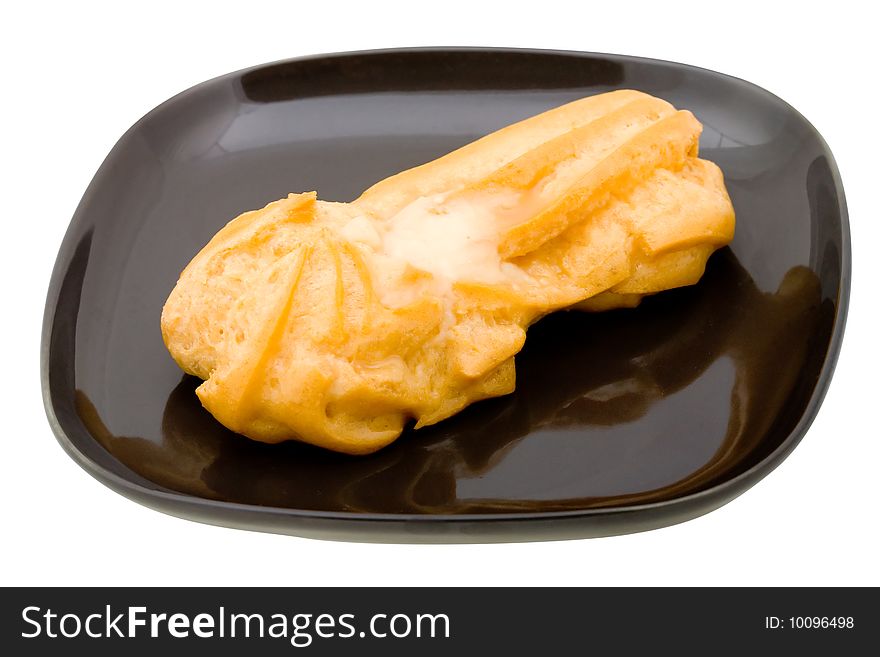 Fresh cake (eclair) on black plate. Isolated on white background. Fresh cake (eclair) on black plate. Isolated on white background