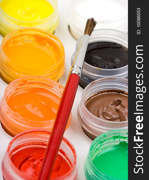 Group of colorful paint cans with brush to background