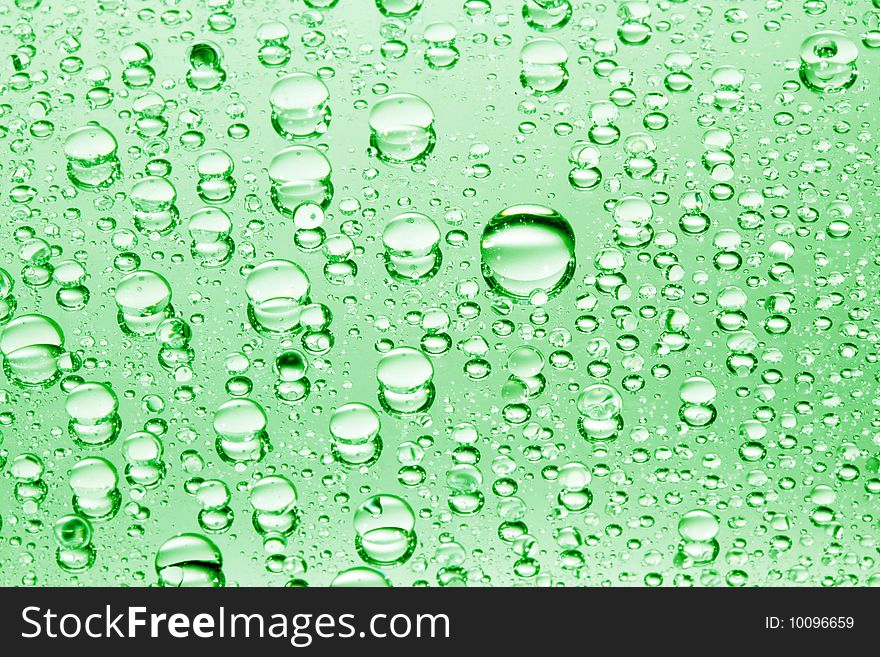 Green water drops against mirror