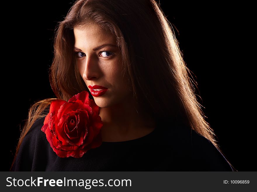 Portrait of a young beautiful brunettes with red lips in a black blouse decorated with a rose. Portrait of a young beautiful brunettes with red lips in a black blouse decorated with a rose