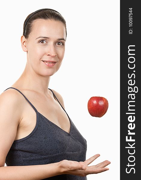 A young healthy woman tossing an apple on a white background. A young healthy woman tossing an apple on a white background.