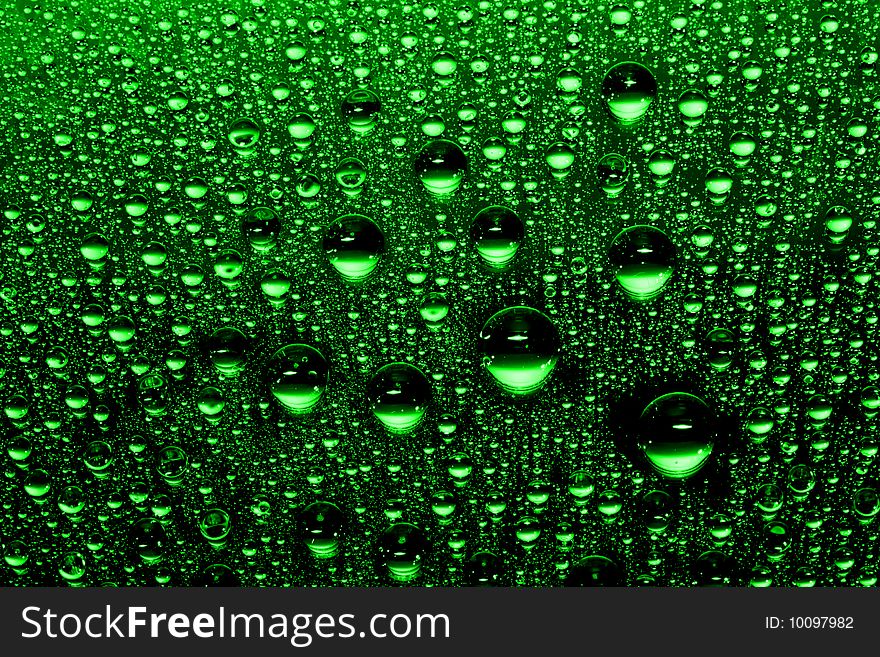 Green water drops against black background