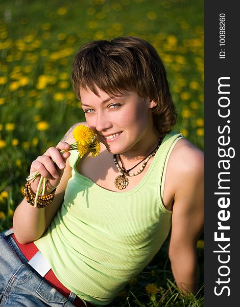 A young cheerful woman having fun on a dandelions glade