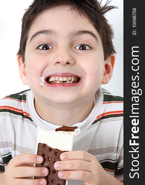Adorable happy six year old boy eating icecream sandwiches. Adorable happy six year old boy eating icecream sandwiches.
