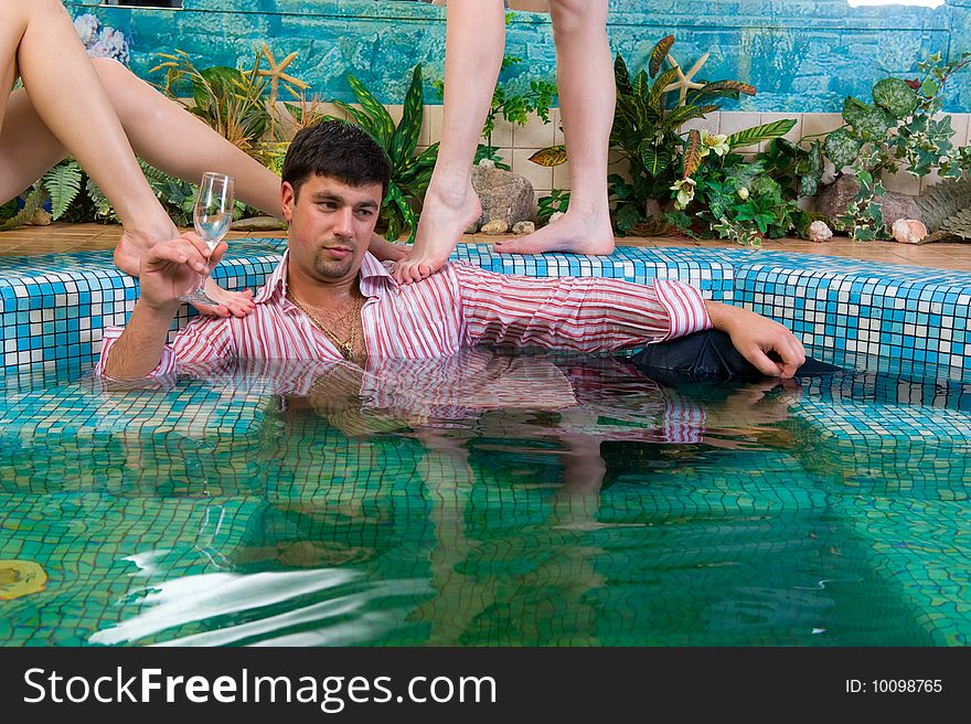 Handsome young man in a pool surrounded by women's feet. Handsome young man in a pool surrounded by women's feet