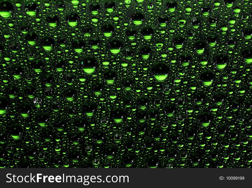 Green water drops against black background