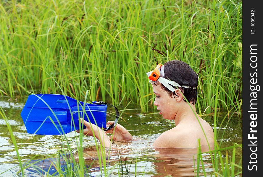 The boy fixing his fin sitting in the water. The boy fixing his fin sitting in the water.