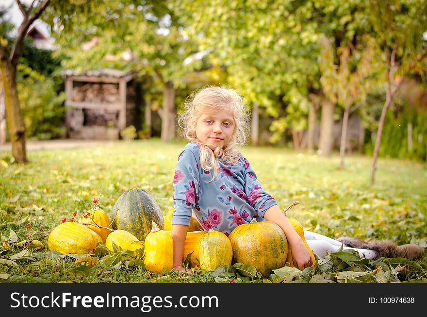 Beautiful blond girl with orange pumpkins in green autumn garden. Beautiful blond girl with orange pumpkins in green autumn garden