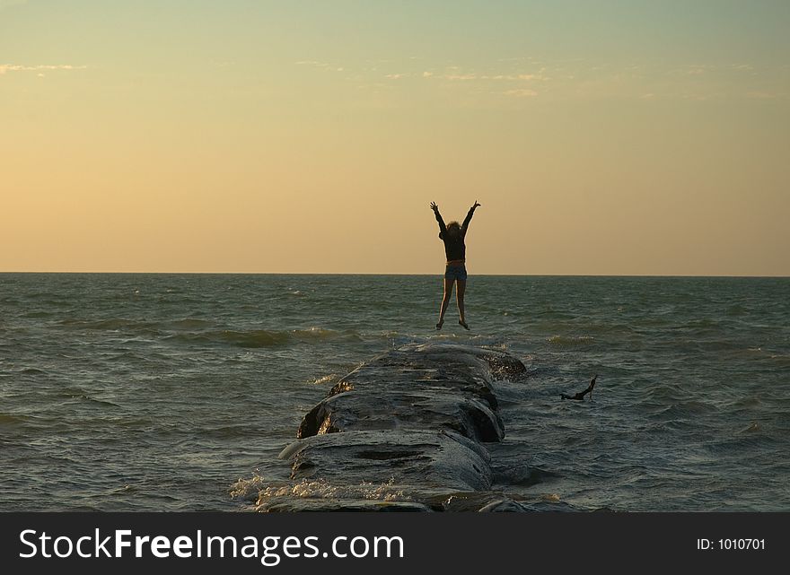 Girl jumping on a rock at sunset in Holbox, Caribbean, Mexico