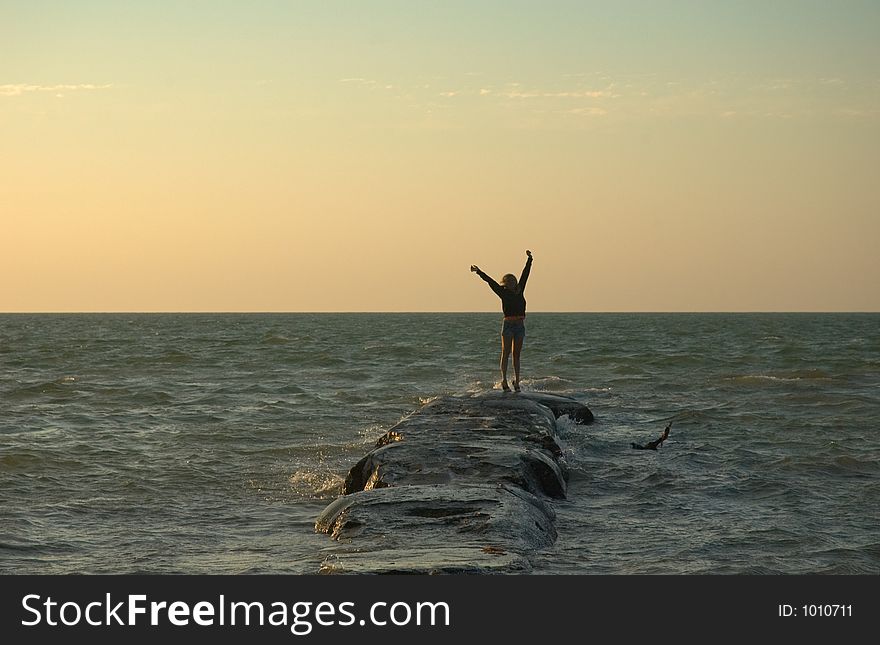 Girl jumping on a rock at sunset in Holbox, Caribbean, Mexico