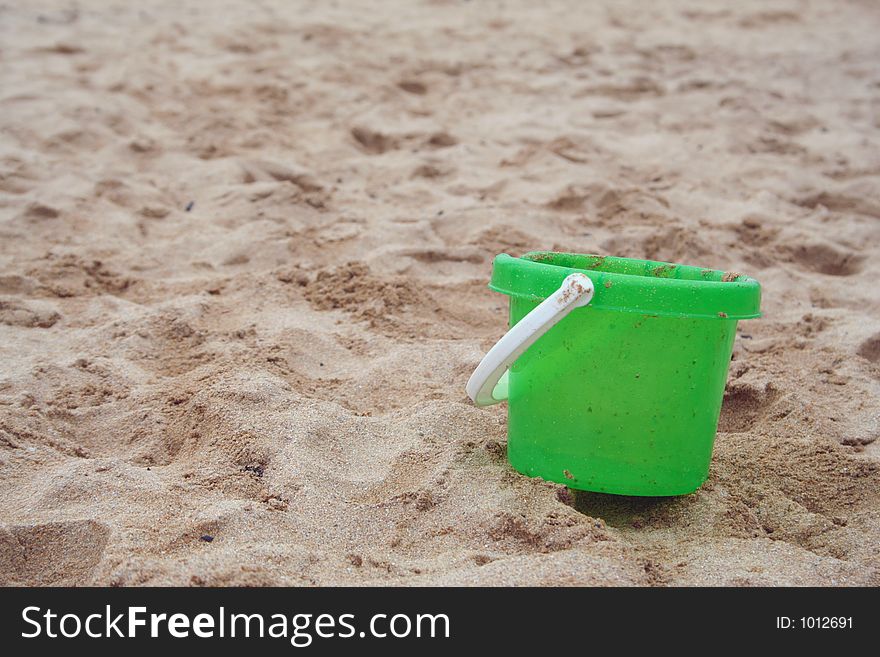 Green bucket left on the beach