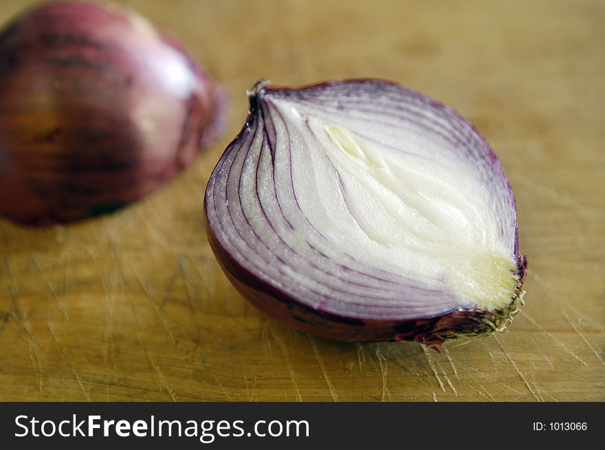 A Red or Purple onion sliced in half on a chopping board. A Red or Purple onion sliced in half on a chopping board