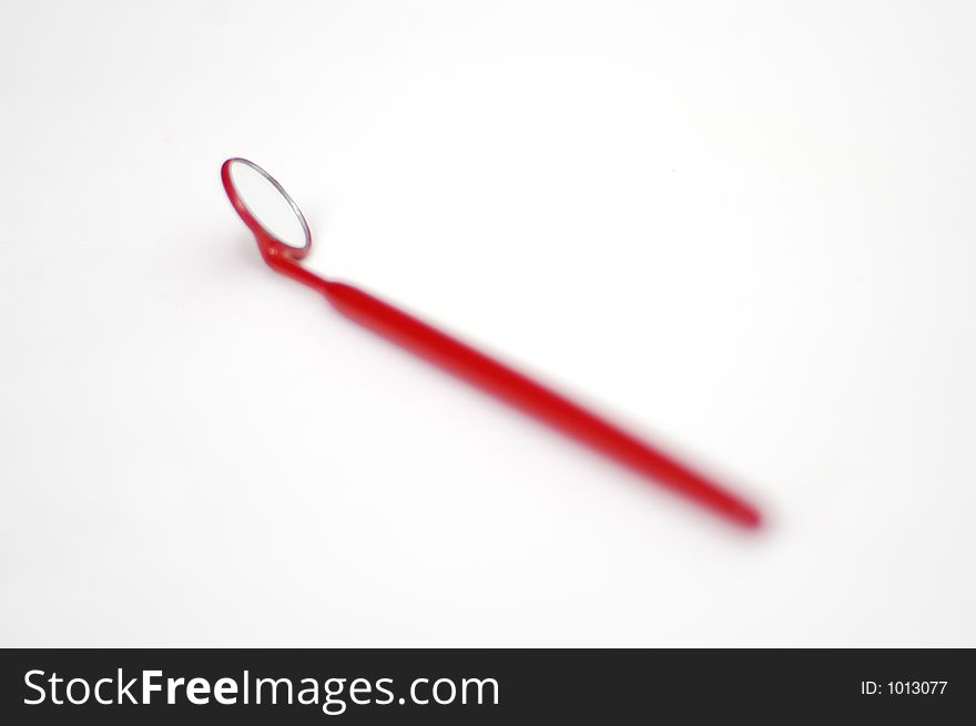 A small inspection mirror for electronics on a red handle in shallow DOF on white. A small inspection mirror for electronics on a red handle in shallow DOF on white