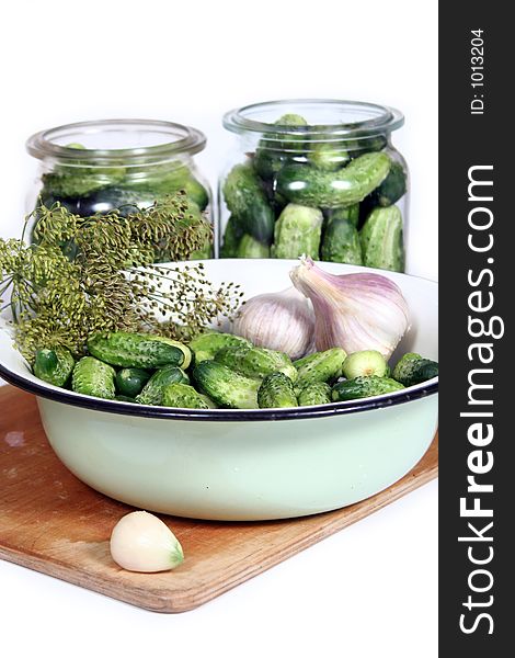 A bowl of cucumbers garlic and dill on a cutting board. A bowl of cucumbers garlic and dill on a cutting board