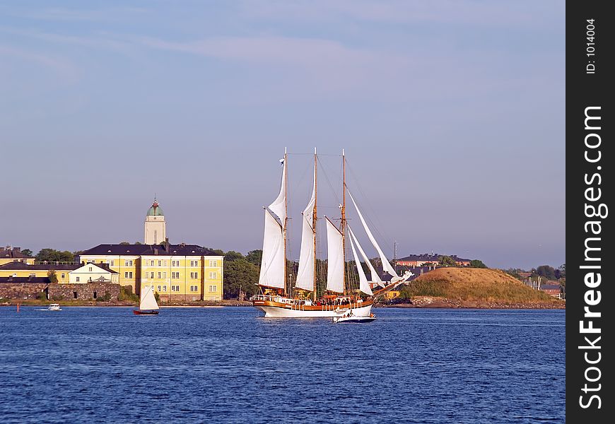 A wooden sails boat near the fortress at sunset