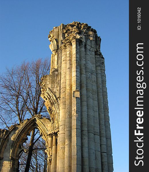 Ruined church pillar and archway in early evening light.