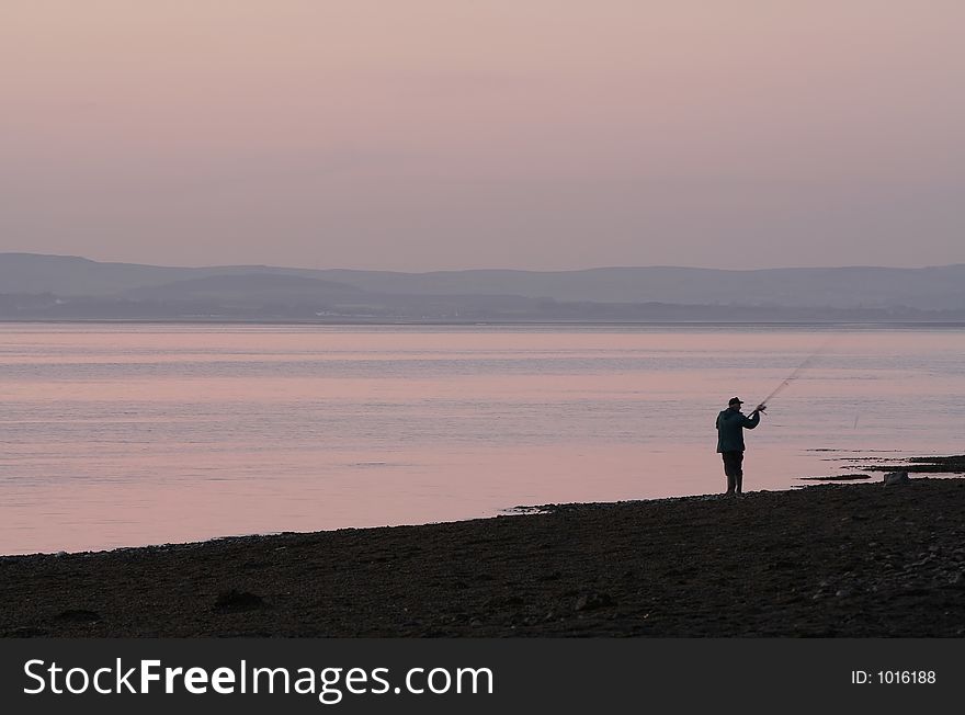 Sea fisherman casts out at dusk. Sea fisherman casts out at dusk