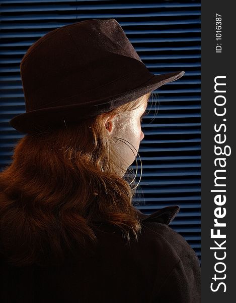 Young girl with a hat in front of a closed venitian blind. Young girl with a hat in front of a closed venitian blind.