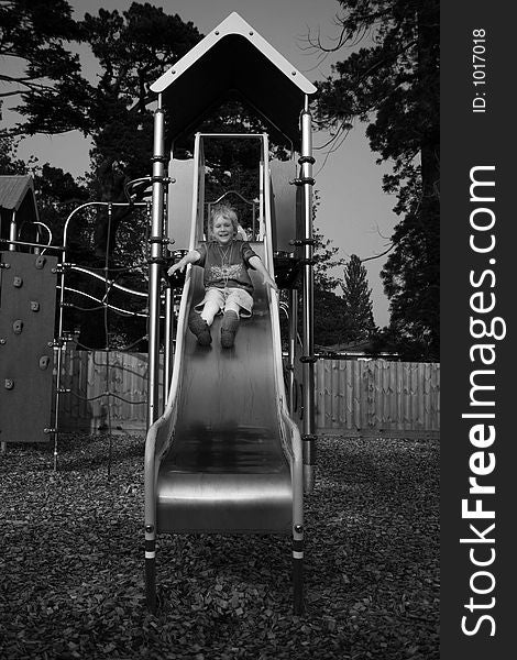 A small child halfway down a playground slide. A small child halfway down a playground slide.