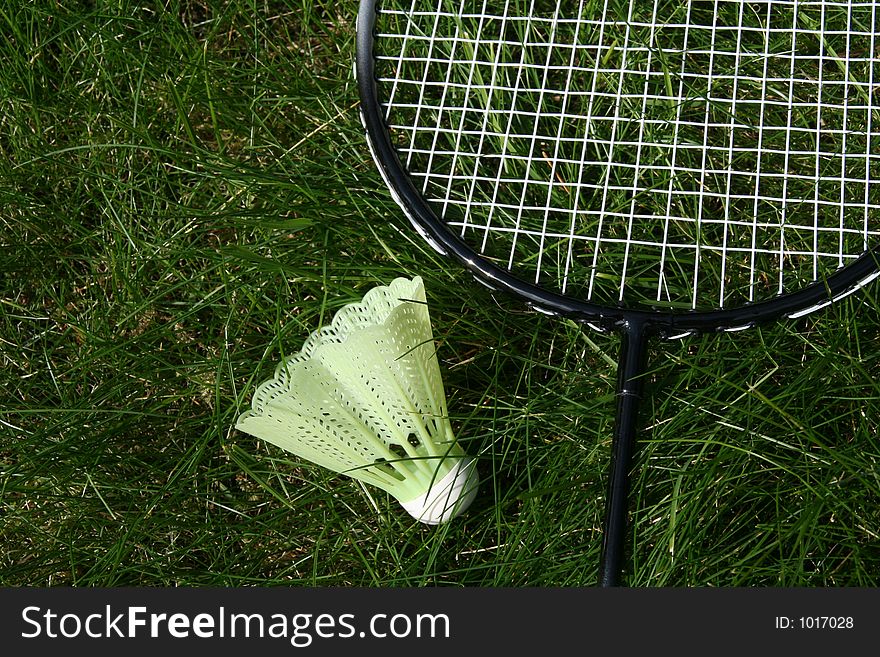 Plastic ball with badmingthon racket laying in the grass. Plastic ball with badmingthon racket laying in the grass