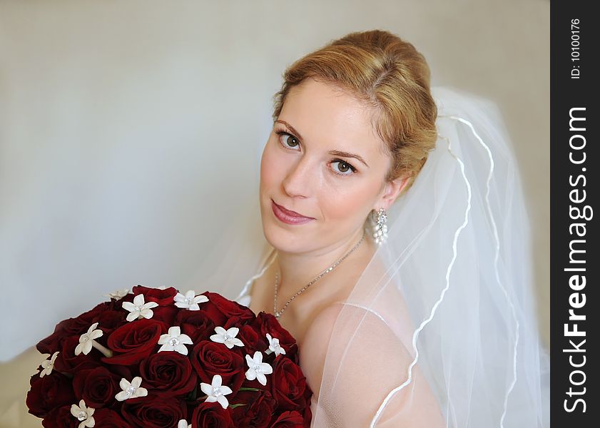 Portrait of a bride with bouquet of red roses with intentionally left copy-space on left side.