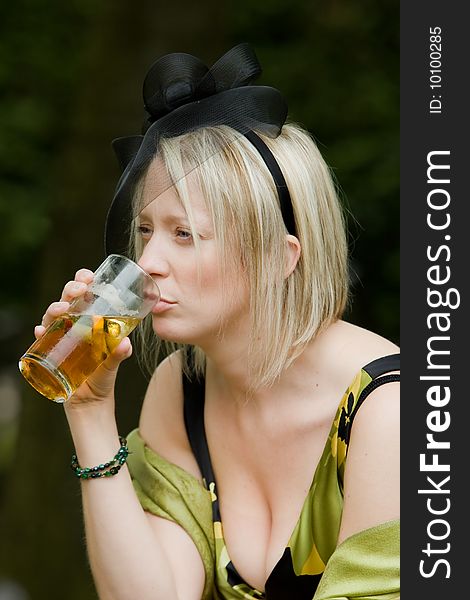 Attractive young woman drinking beer at a summer garden party. Attractive young woman drinking beer at a summer garden party