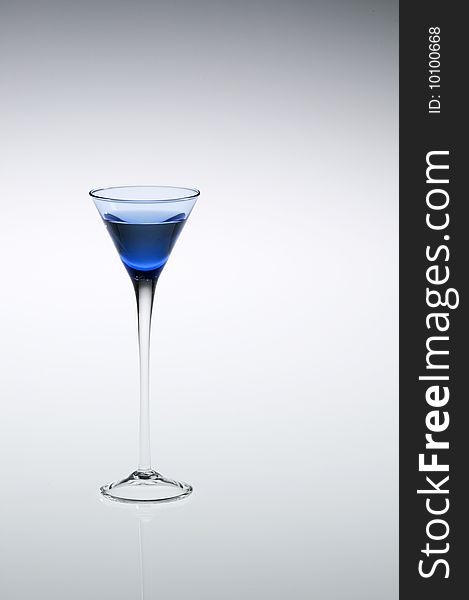 Blue cordial, aperitif, or liqueur glass with stem reflecting, off-center to left of frame. Blue cordial, aperitif, or liqueur glass with stem reflecting, off-center to left of frame.
