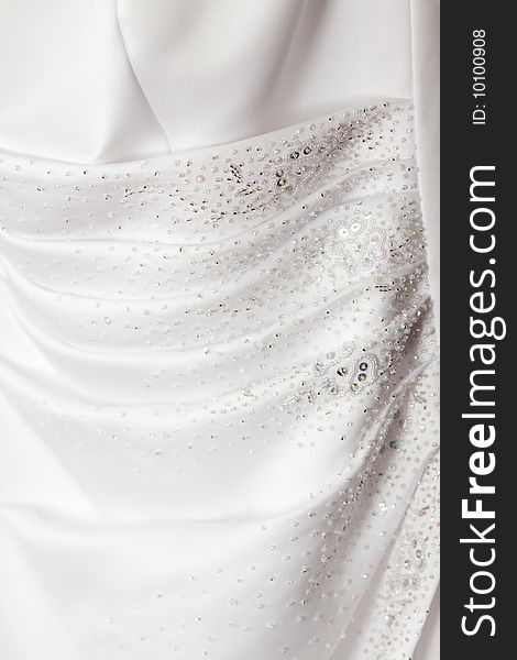 Detail of the white wedding dress that a bride will wear to her wedding ceremony and reception. Detail of the white wedding dress that a bride will wear to her wedding ceremony and reception.