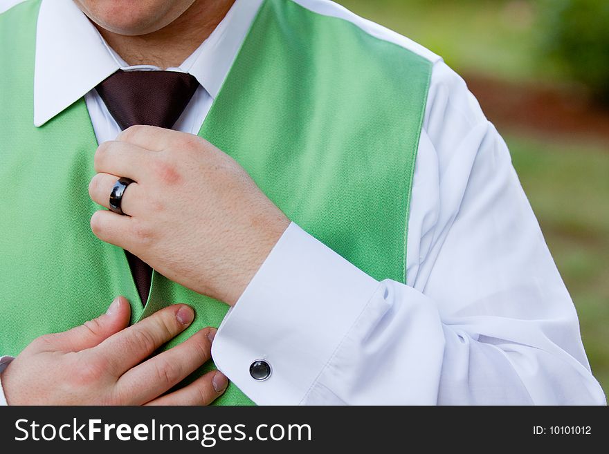A groom is messing with his tie and vest at a wedding reception. A groom is messing with his tie and vest at a wedding reception.
