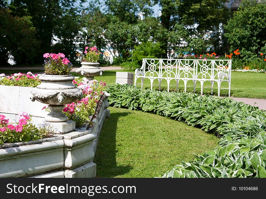 Flower-bed in a summer garden with a bench