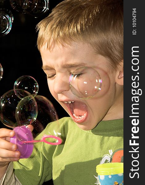 Young boy blowing bubbles outside in the sun