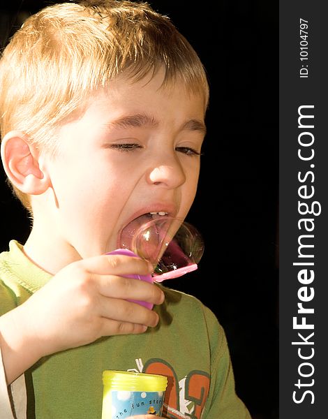 Young boy blowing bubbles outside in the sun