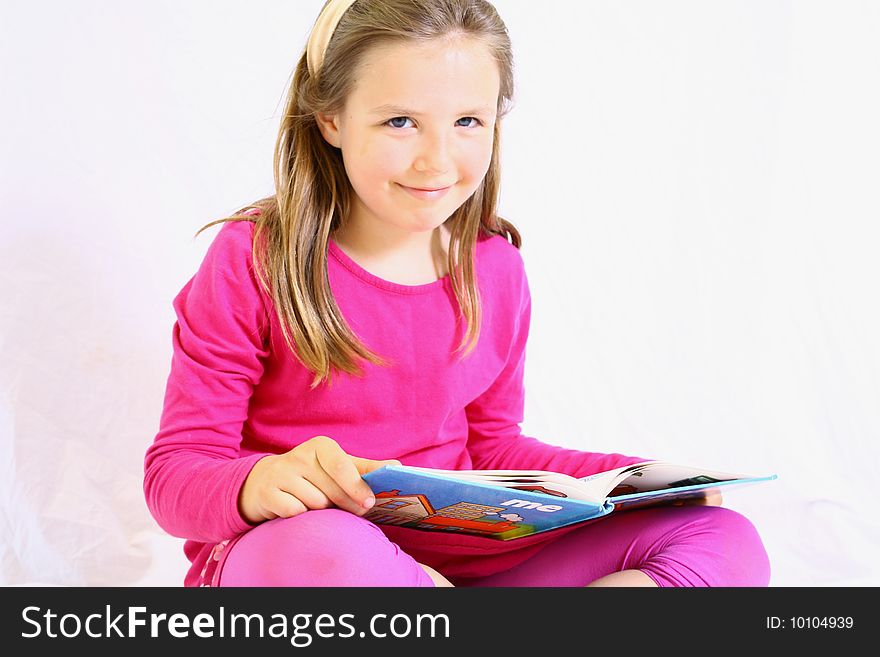 Young cute girl with pink dress reading book. Young cute girl with pink dress reading book.