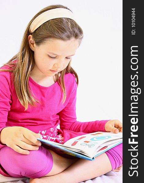 Young cute girl with pink dress reading book. Young cute girl with pink dress reading book.