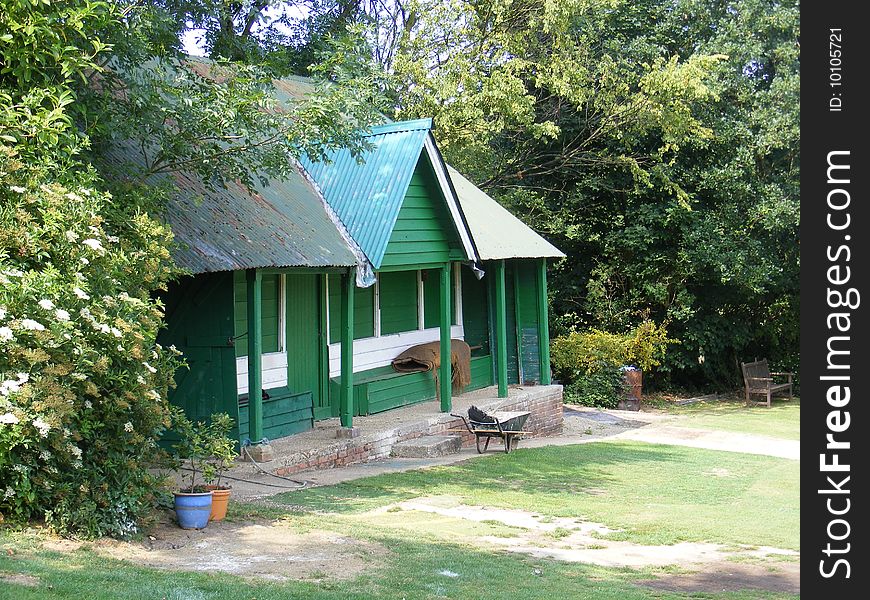 Abandoned green and white cricket pavillion and wheelbarrow. Abandoned green and white cricket pavillion and wheelbarrow