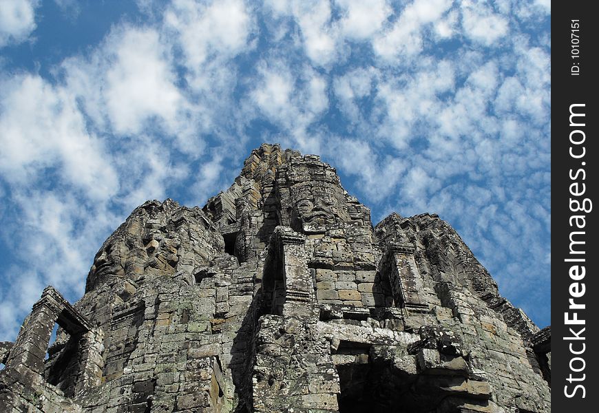 Image of a temple in angkor that has many rock formed faces.