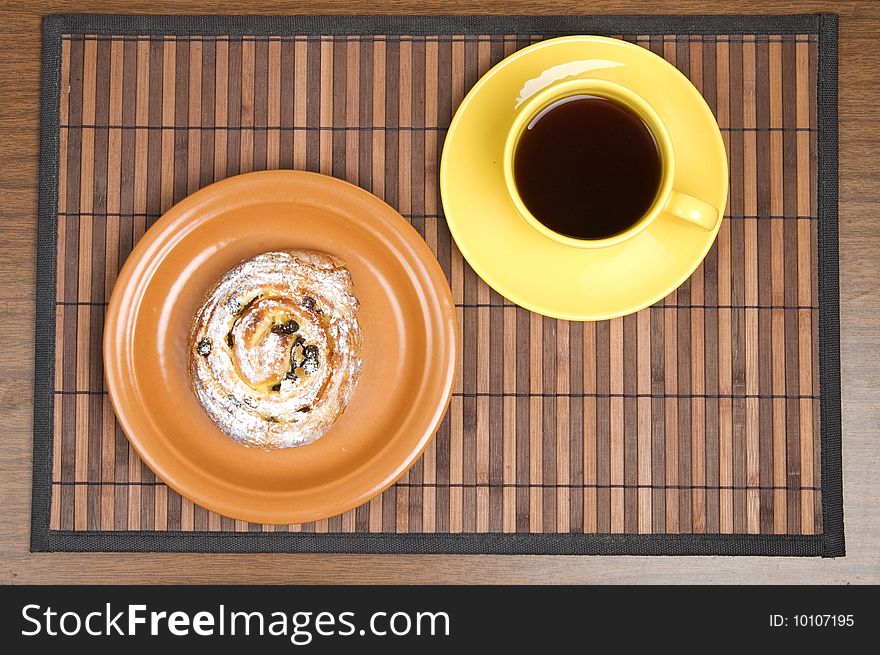 Sweet bun and yellow tea cup. Sweet bun and yellow tea cup