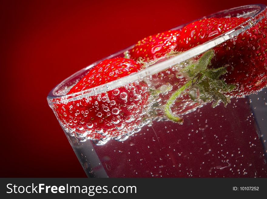 Three strawberry in a glass with water