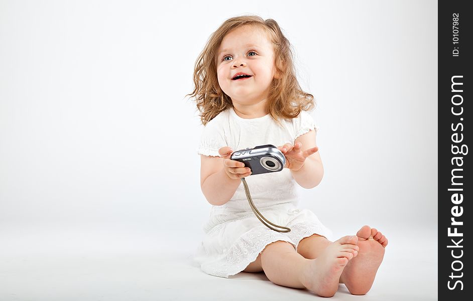 Little girl with camera on gray background