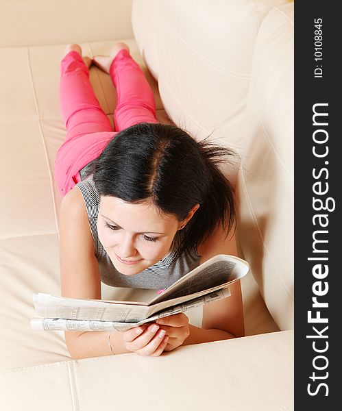 Girl reading a newspaper and sofa