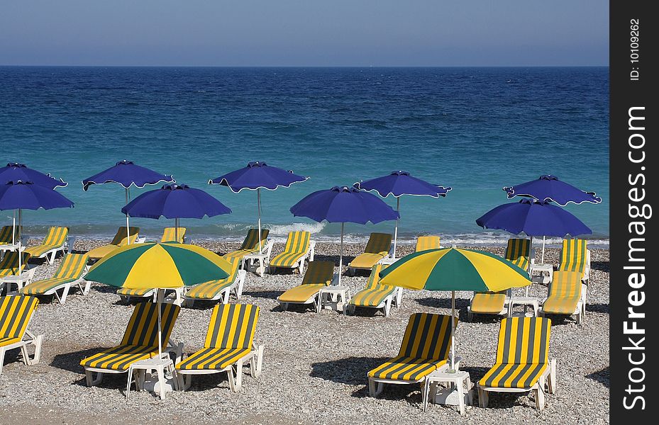 Beach with sun loungers and umbrellas near the blue sea. Beach with sun loungers and umbrellas near the blue sea