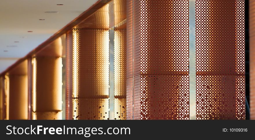 A corridor lighted by fluorescent lights inside perforated metal columns. A corridor lighted by fluorescent lights inside perforated metal columns