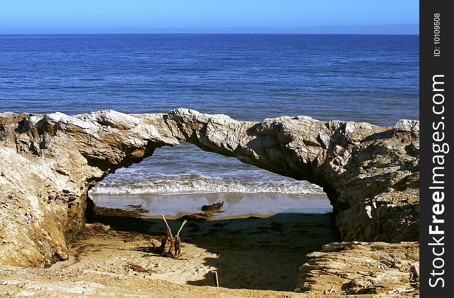 A rocked in the shape of a bridge near the beach. A rocked in the shape of a bridge near the beach