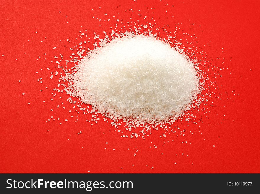 Sugar grains over red background.