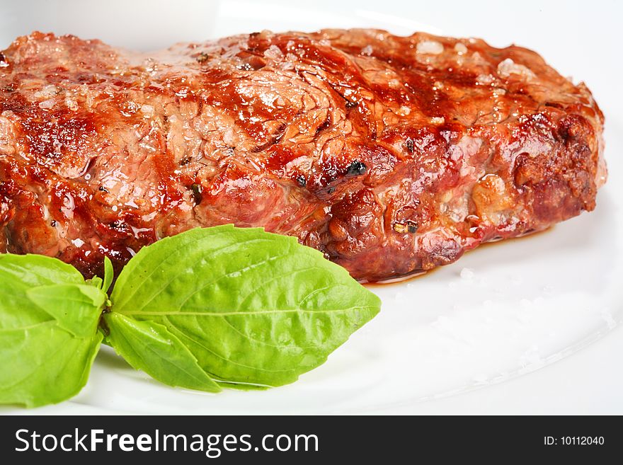 Juicy beef steak on the white plate with oregano leaf