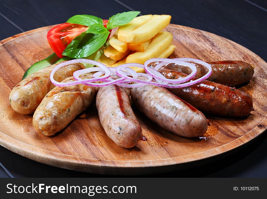 Assortment of grilled sausages on the wooden plate