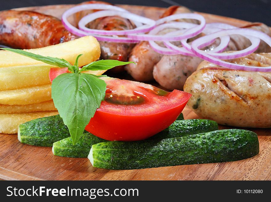 Assortment of grilled sausages on the wooden plate