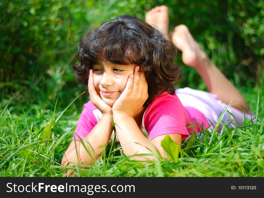 A little female child laying on the grass outdoor. A little female child laying on the grass outdoor