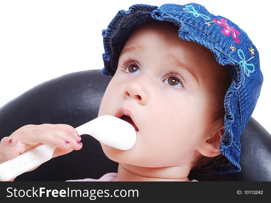 Baby sitting on the black chair and eating isolated in white